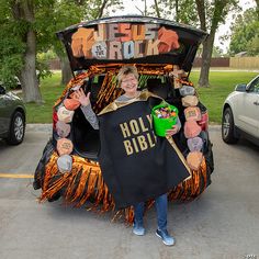 a woman holding up a large black blanket with words on it in the shape of a car trunk