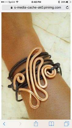 a woman's arm wearing a leather bracelet with two metal spirals on it