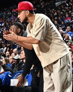 a man with a red hat on standing in front of a crowd at a basketball game