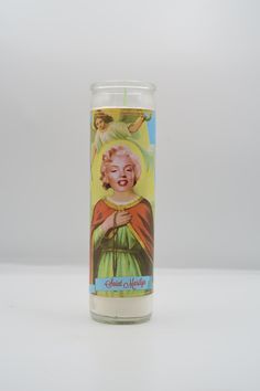 a candle with a painting of a woman holding a flower in her right hand, on a white background