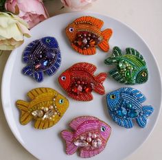 six colorful fish on a white plate next to flowers