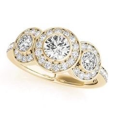 a yellow gold ring with three round diamonds on the band and an oval center stone