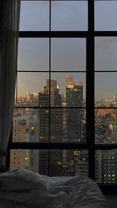 a bedroom with a view of the city from it's large window sill