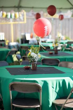 tables with green tablecloths and balloons in the air at a sports themed birthday party