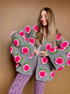 a woman is posing for the camera wearing a sweater and pants with flowers on it