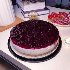 a cheesecake covered in blueberry sauce sitting on top of a table next to a stack of books