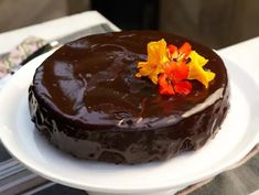 a chocolate cake on a white plate with flowers in the middle and one flower sticking out of it