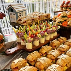 an assortment of sandwiches and pastries on display at a buffet or party with flowers in vases