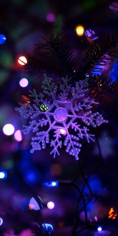 a purple snowflake sitting on top of a christmas tree covered in multicolored lights