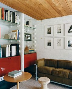 a living room filled with furniture and bookshelves next to a white brick wall