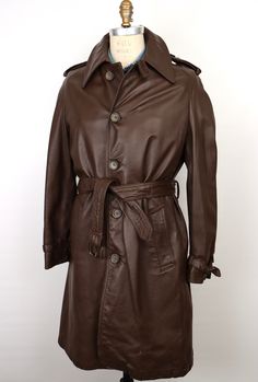 "\"The Leader of the Pack\" vintage 1970s leather trench coat in rich dark chocolate brown leather with matching marbled brown buttons, featuring: belted front with belt loops on sides/back and dark metal buckle; wide, deeply notched \"Ulster-style\" collar, which can lay flat or be popped up; 5-button front with top collar button and buttonhole loop for closing all the way up; angled front/hip pockets with cuffs; center vented back; and stylish knee length--A true vintage statement piece--Beaut Formal Leather Belted Outerwear, Belted Brown Outerwear For Business, Formal Leather Outerwear With Belt Loops, Classic Leather Outerwear With Belt Loops, Vintage Leather Outerwear For Business, Vintage Leather Business Outerwear, Vintage Belted Outerwear For Formal Occasions, Belted Vintage Outerwear For Formal Occasions, Leather Trench Coat Mens