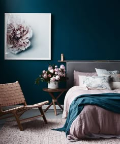 a bedroom with blue walls and pink bedding in the corner, along with two chairs