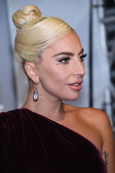 lady with blonde hair and big earrings looking off to the side, wearing purple velvet dress