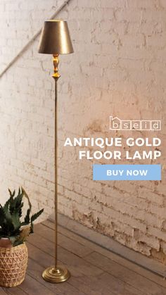 an antique gold floor lamp is on display in front of a brick wall and potted plant