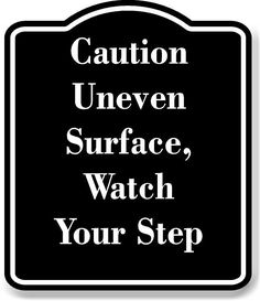 a black and white sign with the words caution uneven surface, watch your step on it