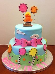 a three tiered cake decorated with colorful frosting and cartoon characters on the top