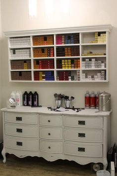 a white dresser with lots of bottles on top of it and shelves filled with books