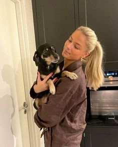 a woman holding a small dog in her arms while standing next to a microwave oven