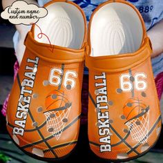 an orange pair of basketball shoes with the number 66 on them is being held by a child