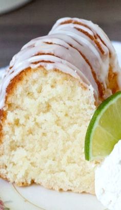 a piece of cake with frosting and a lime slice on the plate next to it