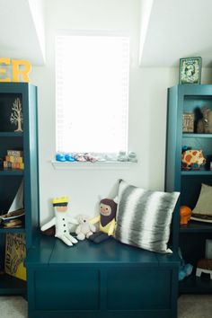 there is a blue book shelf with stuffed animals on it