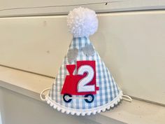 a blue and white birthday hat with the number two on it's side hanging from a window sill