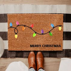 a person standing in front of a door mat with christmas lights on it