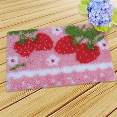 a pink rug with strawberries and blue hydrangeas on it sitting on a wooden floor