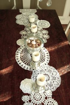 a long table with candles and doily on it