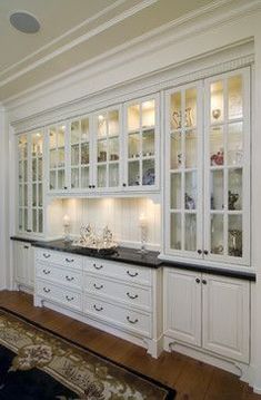 a large kitchen with white cabinets and black counter tops, along with an area rug on the floor