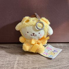 a yellow stuffed animal with a keychain on it's neck sitting on a table