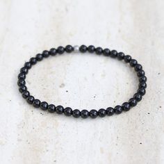 Shungite Delicate Bracelet Add a powerfully protective and comfortable Shungite bracelet to your stack! Made with genuine Shungite. Delicate & lightweight, perfect for everyday wear! Strung on our exclusive, thick, hitec elastic. Available in 3 sizes! Made in the USA. Ships in 1 Business Day! Shungite is also called "Miracle Stone" or "Stone of Life" as it is a very powerful stone known to protect the wearer, and it is very grounding. Bead size: 4mm SMALL: 6.5 inches/ 16.5 cm MEDIUM: 7.25 inches Minimalist Black Bracelet For Meditation, Minimalist Black Bracelets For Meditation, Spiritual Black Hypoallergenic Bracelets, Spiritual Hypoallergenic Black Bracelets, Hypoallergenic Black Spiritual Bracelets, Hypoallergenic Black Bracelets For Meditation, Minimalist Black Beaded Bracelets For Meditation, Black Hematite Crystal Bracelet For Spiritual Use, Black Hematite Crystal Bracelet Spiritual