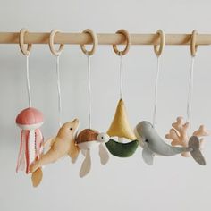 three wooden toys hanging from hooks on a white wall with mushrooms, sea animals and seashells