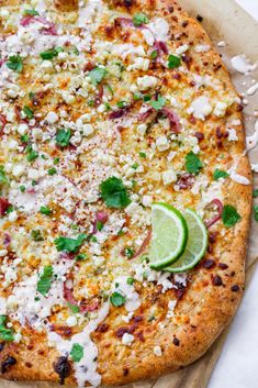 a pizza topped with cheese, meat and garnish on a wooden cutting board