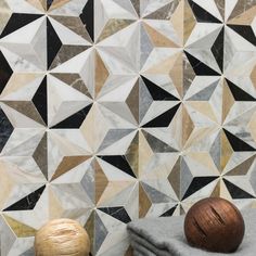 two wooden balls sitting on top of a towel next to a wall covered in geometric tiles