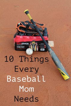 a baseball bat laying on top of a field next to a bag and ball cap