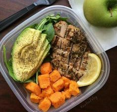 a plastic container filled with meat and veggies on top of a wooden table