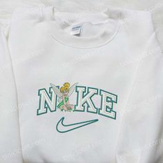 The Tinkerbell x Nike Cartoon Embroidered Sweatshirt is a delightful collaboration between two iconic brands. Featuring Tinkerbell, the beloved Disney character, intricately embroidered on a cozy sweatshirt, this piece is a must-have for any Disney enthusiast. The vibrant colors and high-quality stitching bring the magical world of Disney to life. Made with premium materials, this sweatshirt offers both comfort and style. Whether you’re a fan of Tinkerbell or simply love unique and eye-cat Embroidered Nike Crewnecks, Nike Embroidered Sweatshirt, Nike Cartoon, Disney Character Shirts, Nike Inspired, Nike Sweatshirt, Nike Sweatshirts, Embroidered Clothes, Inspirational Celebrities