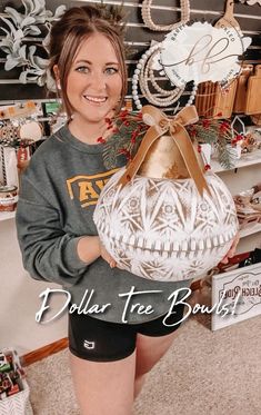 a woman is holding a basket in her hands and smiling at the camera while standing next to a christmas tree