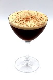 an alcoholic drink in a goblet on a white background with brown sprinkles