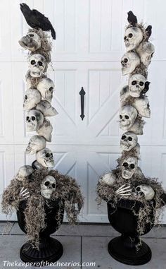 two black vases filled with skulls and birds on top of each other in front of a garage door