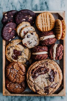 a wooden box filled with assorted cookies and cookies on top of a marble counter