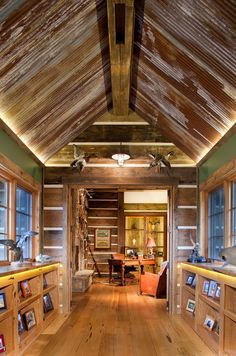 the inside of a log cabin with pictures on the walls and wood floors, along with several windows