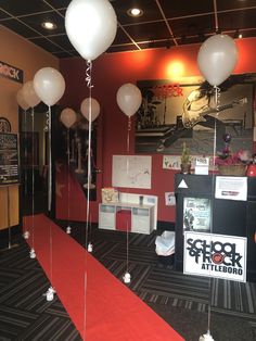 some white balloons are hanging from the ceiling in front of a red carpeted room