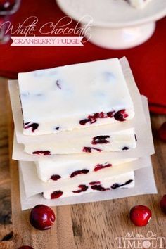 white chocolate and cranberry fudge are stacked on top of each other with cherries in the background