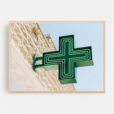 a green cross hanging from the side of a building