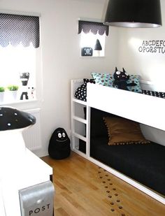 a white bunk bed sitting next to a black and white cat pillow on top of a wooden floor