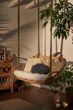 a hanging chair with pillows on it next to a potted plant