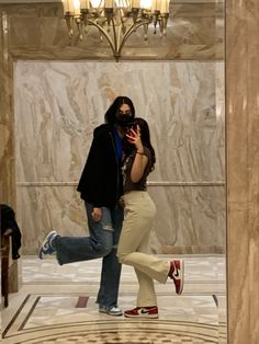 two people are standing in the middle of a marble room and one person is taking a selfie