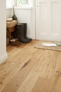 an image of a wooden floor in the entryway with boots and rugs on the floor